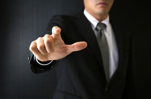 こちらを指さすスーツの男性